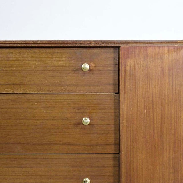 Vintage British mid-century teak sideboard with smooth wood grain, three drawers with brass knobs, and sleek design.