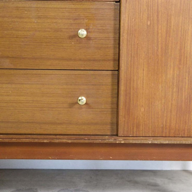 Vintage British mid-century teak sideboard with smooth wood grain, brass knobs, and a clean, rectangular form.