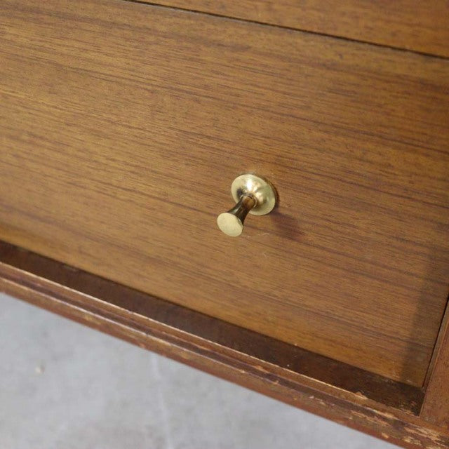 Close-up of vintage British teak sideboard drawer showcasing mid-century wood grain and brass knob detailing.
