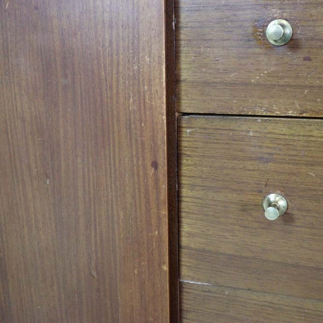 Close-up of vintage British mid-century teak sideboard showing rich wood grain and round metal drawer knobs.