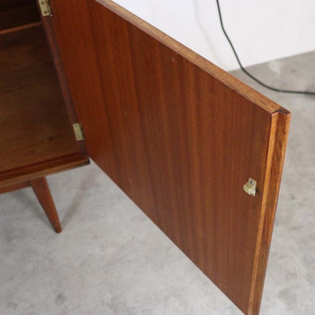 Mid-century British vintage teak sideboard door showing rich wood grain and brass hinge on slender tapered leg base.