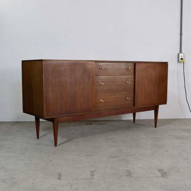 Mid-century British vintage teak sideboard with smooth wood grain, tapered legs, and three central drawers flanked by.