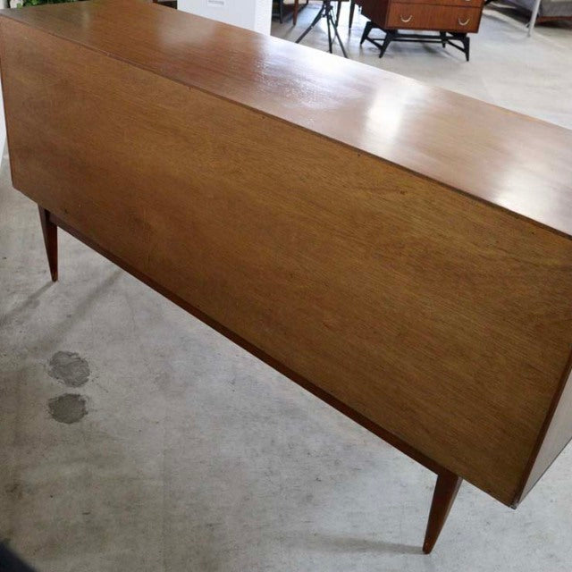 Vintage British mid-century teak sideboard with smooth wood grain and tapered legs, Danish design influence.