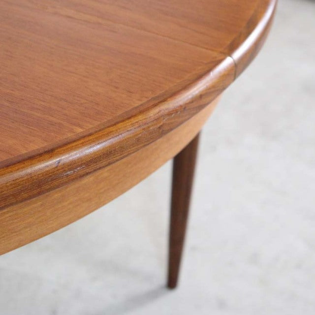 Vintage G-Plan teak dining table corner showing rich wood grain, smooth rounded edge, and slender mid-century British.