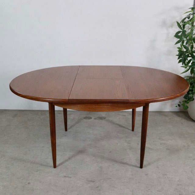 Vintage British mid-century G-PLAN teak dining table with oval top, extending leaf, and tapered legs.