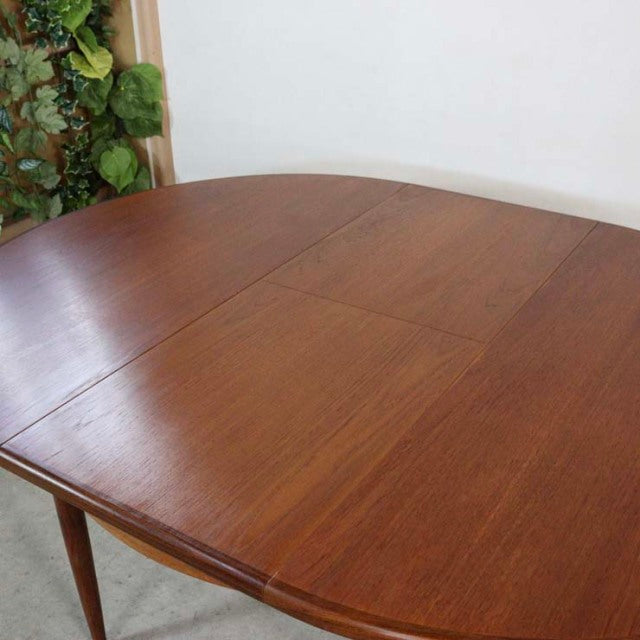 Vintage teak G-Plan mid-century British dining table with oval top, smooth grain, and tapered legs.