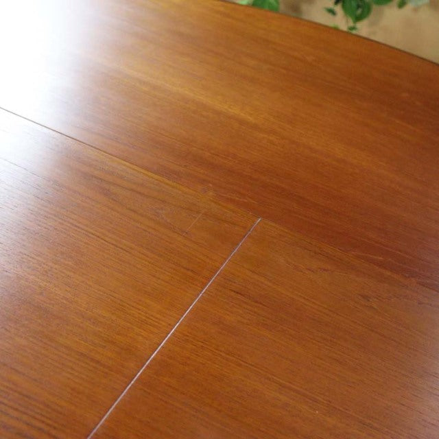 Mid-century British G-Plan vintage teak dining table with smooth grain and extension seam visible on top.