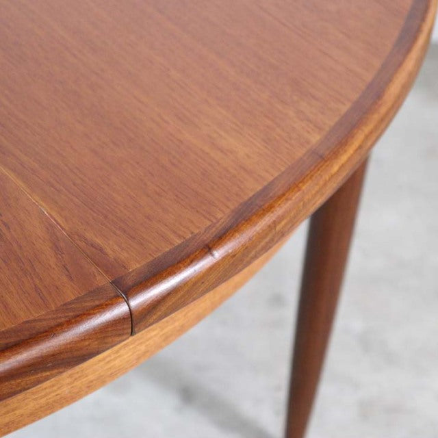 Mid-century British G-Plan vintage teak dining table with smooth oval top and tapered legs.