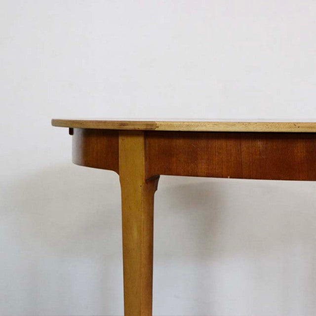 Mid-century British vintage teak dining table with smooth round edge and tapered legs showing natural wood grain.