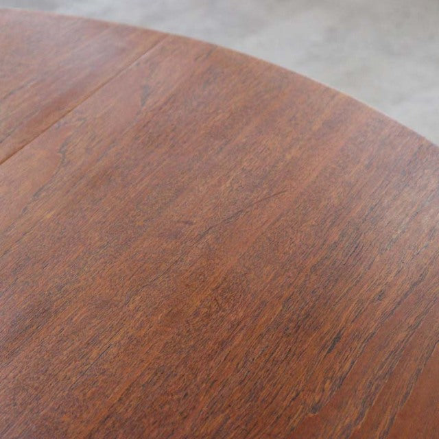 Close-up of vintage mid-century teak dining table top showing rich wood grain and warm British craftsmanship details.