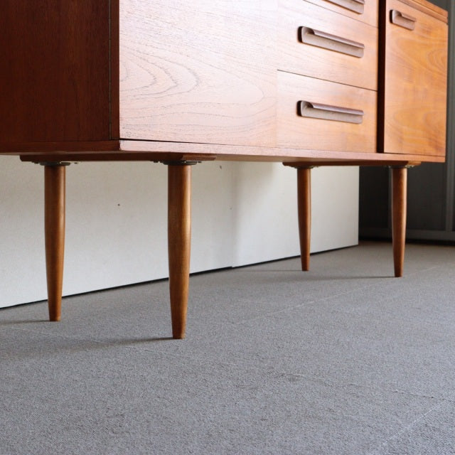 Mid-century British teak sideboard by William Laurence featuring sleek tapered legs and rich wood grain.