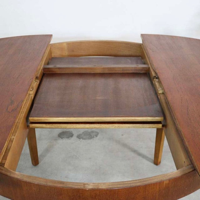 Mid-century British vintage teak dining table with round extendable top and tapered legs, detailed wood grain.