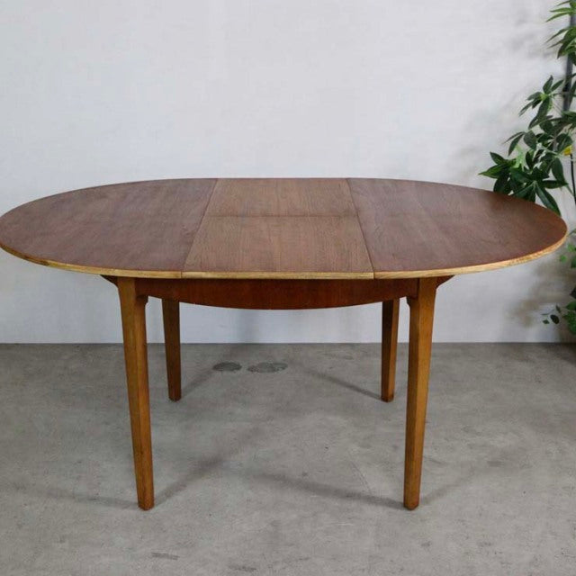 Mid-century British vintage teak round dining table with tapered legs and rich wood grain.