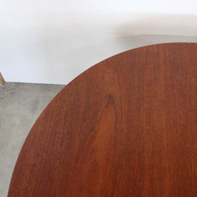 Round mid-century teak dining table with smooth grain top and slender British vintage legs.