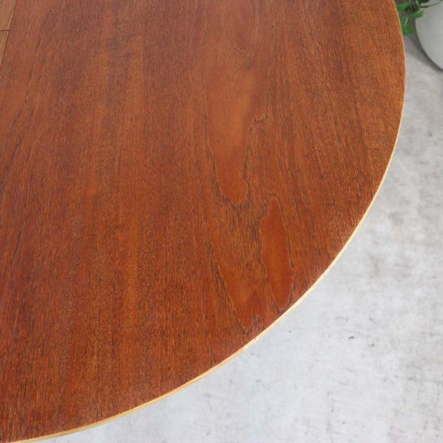 Round vintage teak dining table top showing rich wood grain and warm mid-century British craftsmanship details.