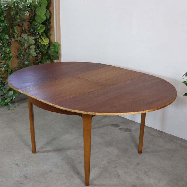 Mid-century vintage British teak oval dining table with smooth wood grain and tapered legs.