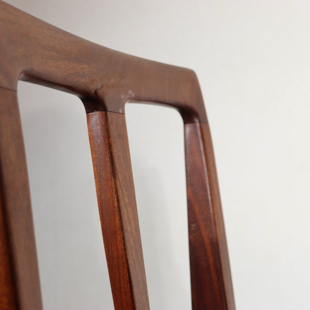 Vintage teak dining chair backrest with sleek, sculpted mid-century British design and visible wood grain from Denmark.