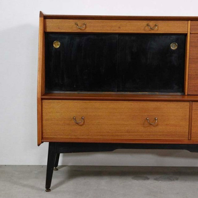 Mid-century British G-Plan Librenza highboard in teak with black sliding doors, brass handles, and tapered black legs.