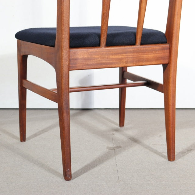 Vintage mid-century teak dining chair with sleek British design, black upholstered seat, slender tapered legs, and visible.