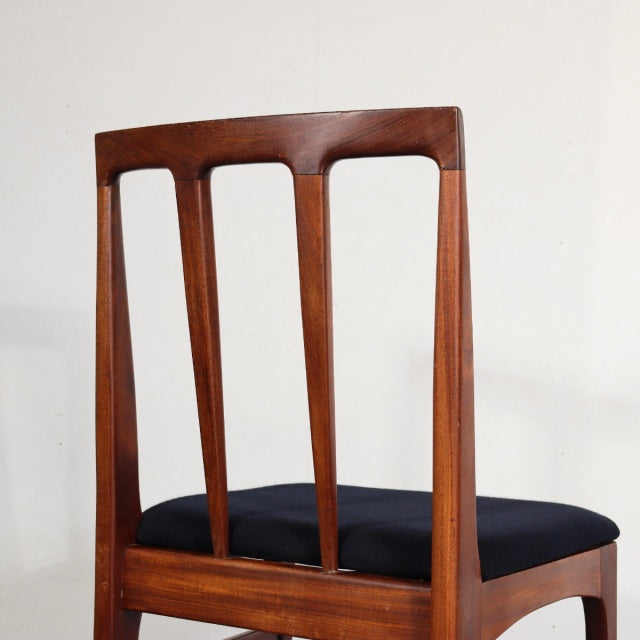 Mid-century British vintage dining chair in teak with a slatted back and black upholstered seat, sleek tapered legs.