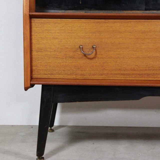 Mid-century British G-Plan teak sideboard with rich wood grain, black tapered legs, and brass handle detailing.