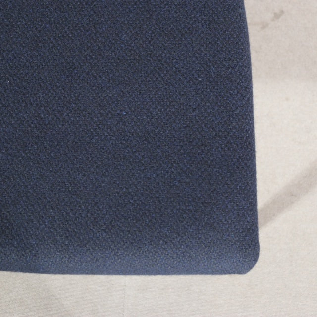 Close-up of dark blue fabric seat cushion on mid-century teak dining chair with smooth wood grain, British vintage style.