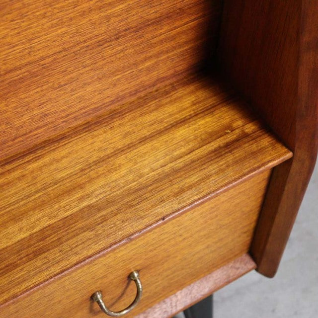 Close-up of vintage British teak highboard corner showcasing rich wood grain, smooth surface, and brass handle detail.
