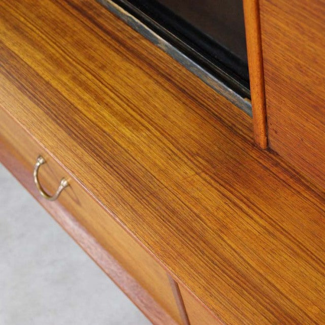 Close-up of vintage British mid-century G-Plan teak sideboard showing rich wood grain, brass handle, and smooth finish.