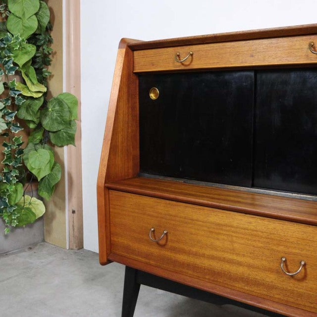 Vintage British G-Plan teak highboard with rich wood grain, black sliding doors, and tapered mid-century legs.