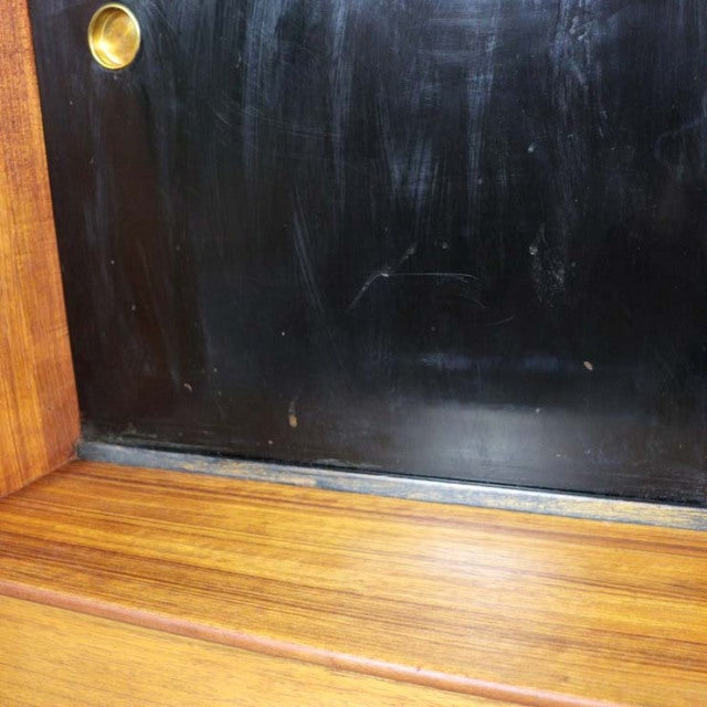 Close-up of vintage G-Plan teak highboard corner with dark black panel and brass detail, mid-century British design, visible .