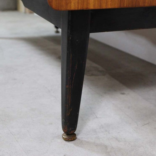 Close-up of tapered black wooden leg with brass foot cap on vintage G-Plan teak mid-century sideboard, showcasing worn.