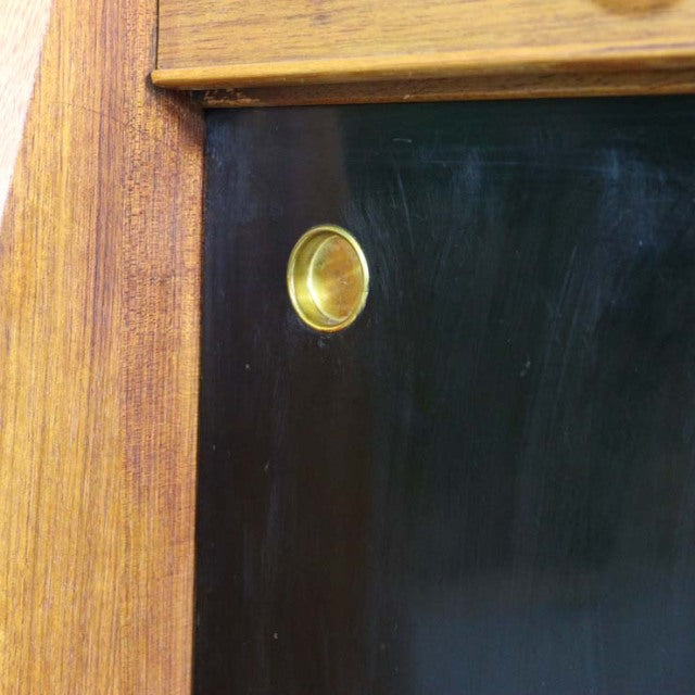 Close-up of mid-century British G-Plan teak highboard corner with visible wood grain and brass knob detailing.