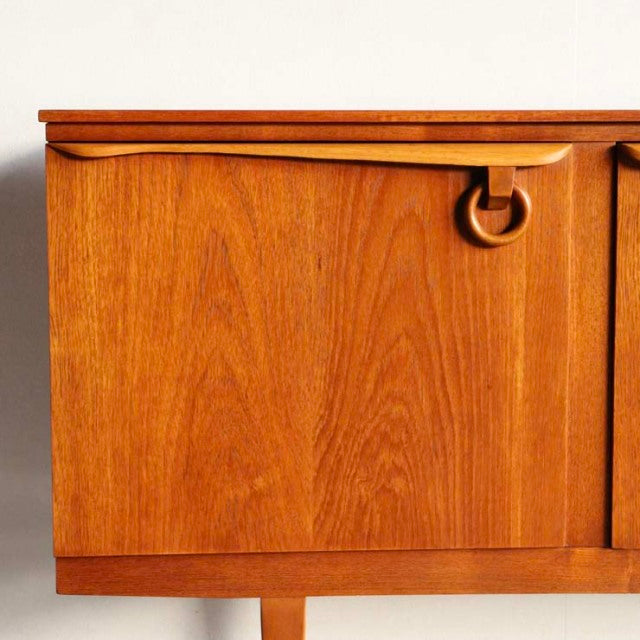 Vintage teak sideboard by Beautility with British mid-century design, smooth wood grain, and distinctive circular handle.