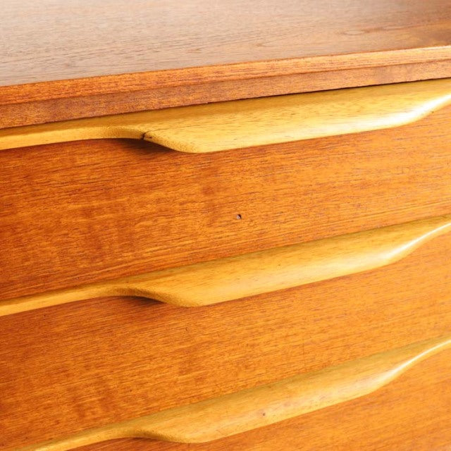 Vintage teak sideboard drawers with smooth curved wooden handles, showcasing mid-century British and Danish craftsmanship.