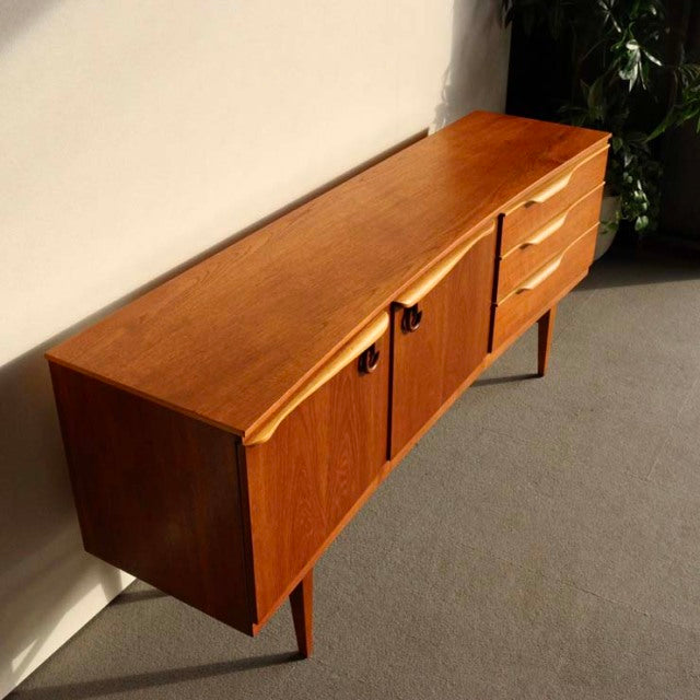 Vintage teak sideboard by Beautility featuring British mid-century design with clean lines, wood grain visible, tapered.