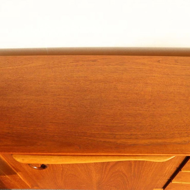 Vintage teak sideboard by Beautility featuring smooth flat top, warm wood grain, and rounded British mid-century Danish legs.