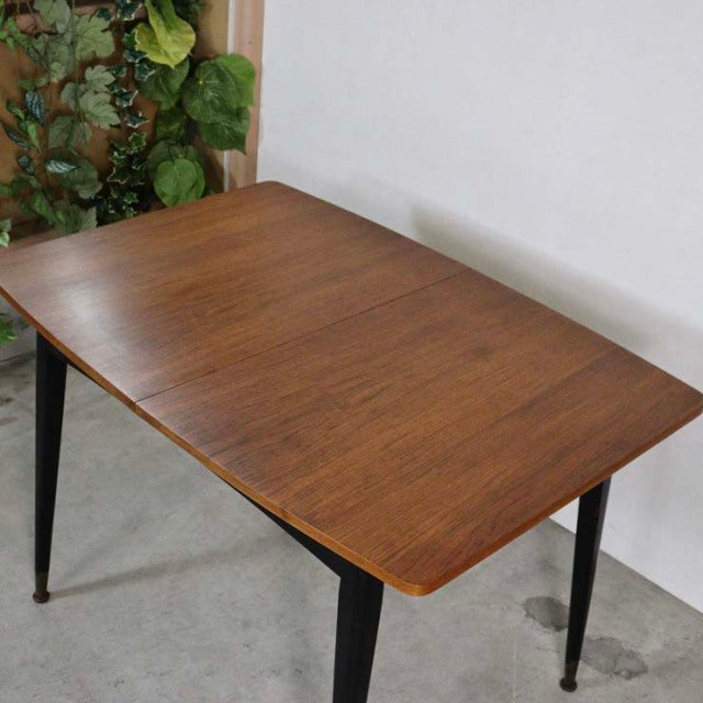 Mid-century British vintage teak dining table with rectangular top and black tapered legs, showcasing rich wood grain.