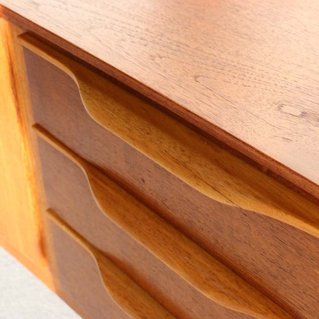 Vintage teak sideboard by Beautility with smooth curved drawer handles, mid-century British-Denmark design, rich wood grain.