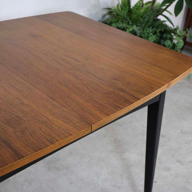 Mid-century vintage British teak dining table with rich wood grain and tapered black legs, rectangular design.