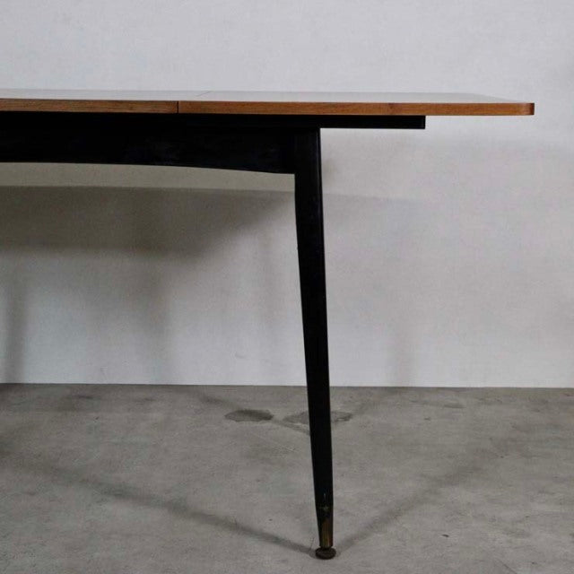 Mid-century British vintage teak dining table with rectangular top and slender black tapered legs from Denmark.