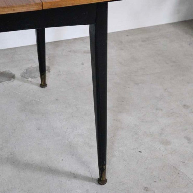 Vintage mid-century teak dining table with slender black tapered legs and brass-capped feet, British-Denmark style showing.