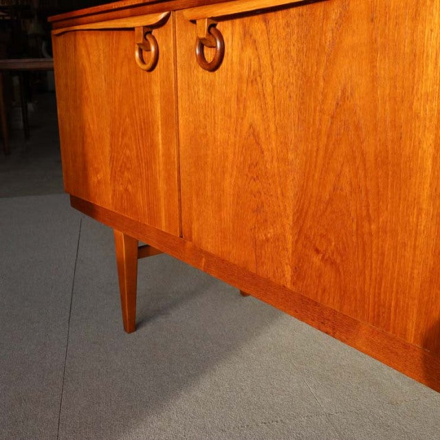 Vintage teak sideboard by Beautility showcasing mid-century British and Danish design, featuring rich wood grain and.
