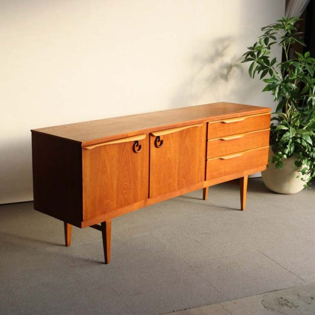 Vintage teak sideboard by Beautility with British mid-century design, curved top, tapered legs, and wood grain detailing.