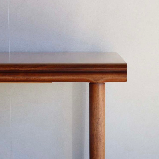 Vintage British mid-century teak dining table corner with smooth wood grain and rounded leg design.