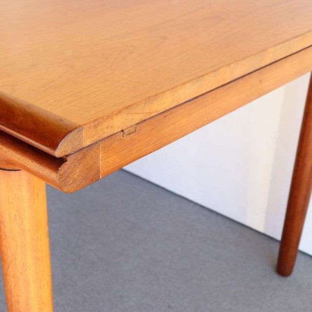 Vintage teak rectangular dining table corner with smooth rounded edges and tapered British mid-century Danish style legs.