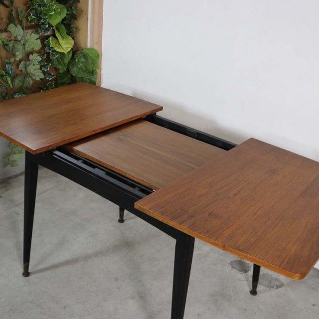 Vintage teak British mid-century dining table with extendable top, tapered black legs, and rich wood grain from Denmark.