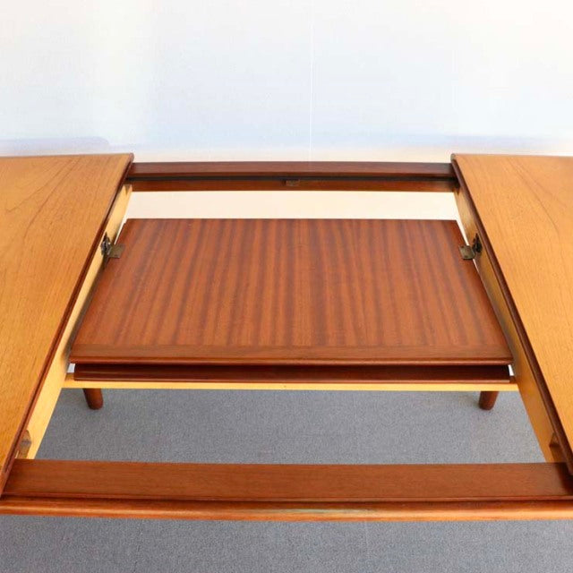 Vintage British mid-century teak dining table by WhiteANDnewton with extending leaf, sleek wood grain and tapered legs.