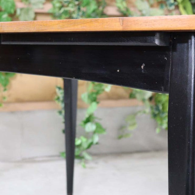Vintage mid-century British teak dining table with black tapered legs and natural wood grain top.