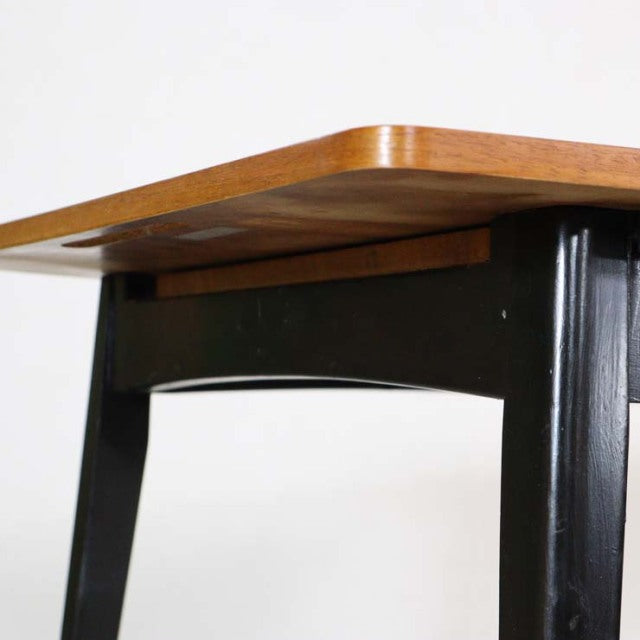 Vintage mid-century British dining table with smooth teak top, rounded edges, and black tapered wooden legs from Denmark.