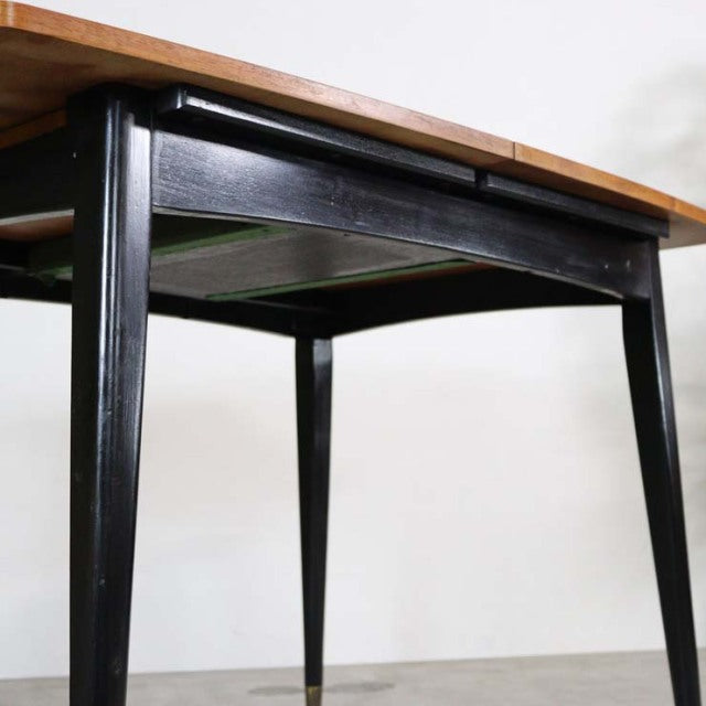 Vintage teak dining table with British mid-century design, tapered black-painted legs, rectangular top, and visible wood.
